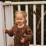 Toddler on a deck in the Honey Blossom Cardi, showing the tie front and buttery dot detail