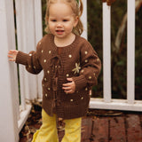 Toddler on a deck in the Buttercup Flares and Honey Blossom Cardi