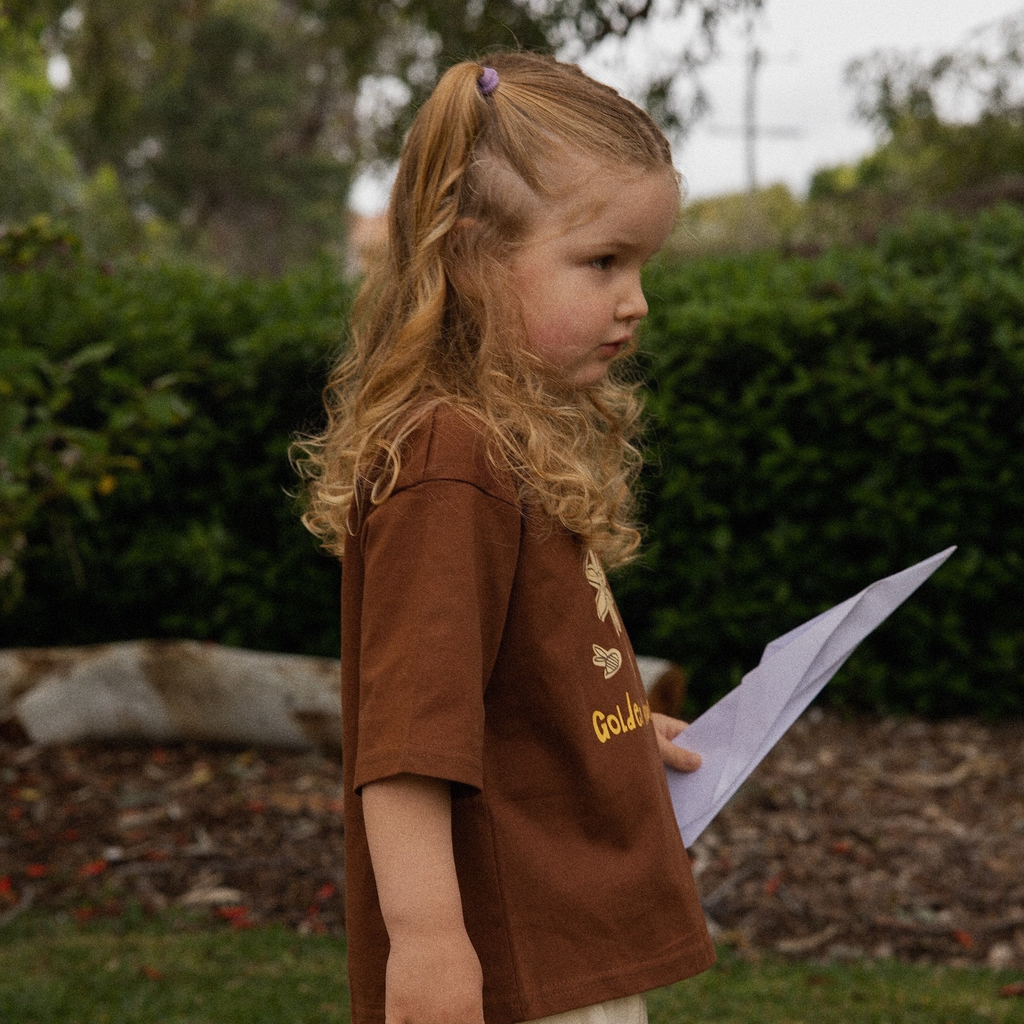 Child in the garden wearing the Golden Hour Garden Tee, showing the hand drawn flower and bee print
