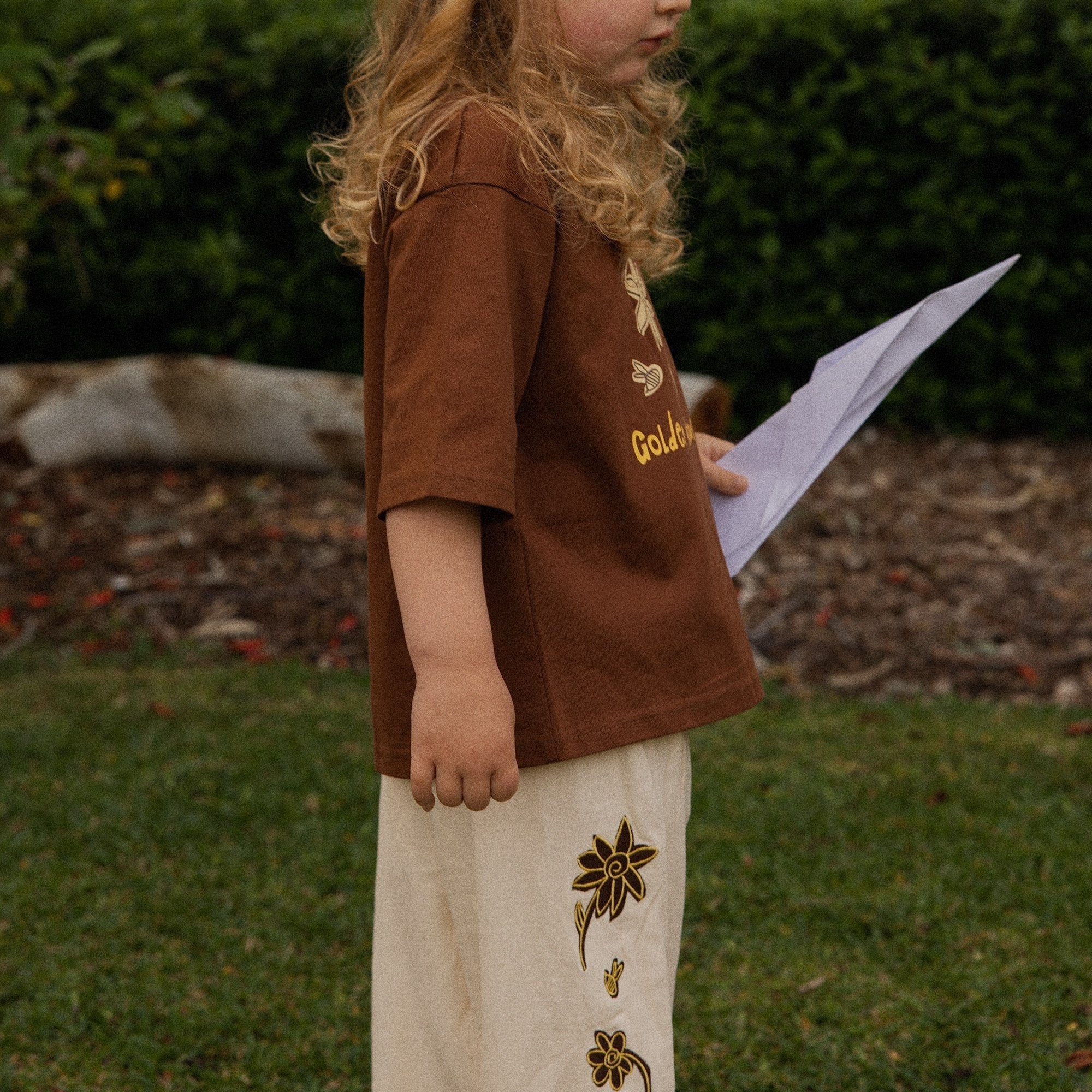 Child in the Let's Pick Flowers Pants in cream linen, embroidered flowers down the leg