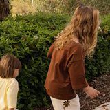 Two children in the garden, one wearing the Golden Hour Garden Tee