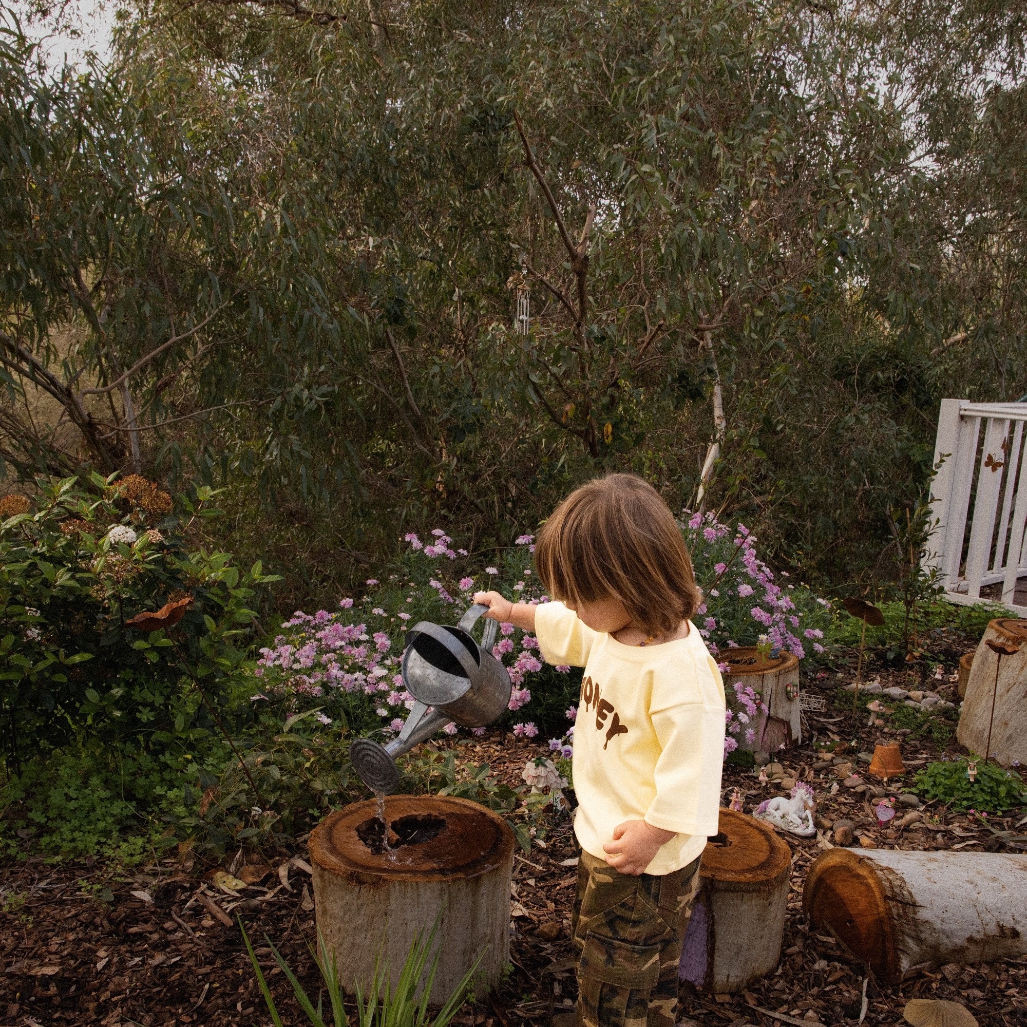 Child watering the garden in the Sweet as Honey Tee and Garden Explorer Cargos