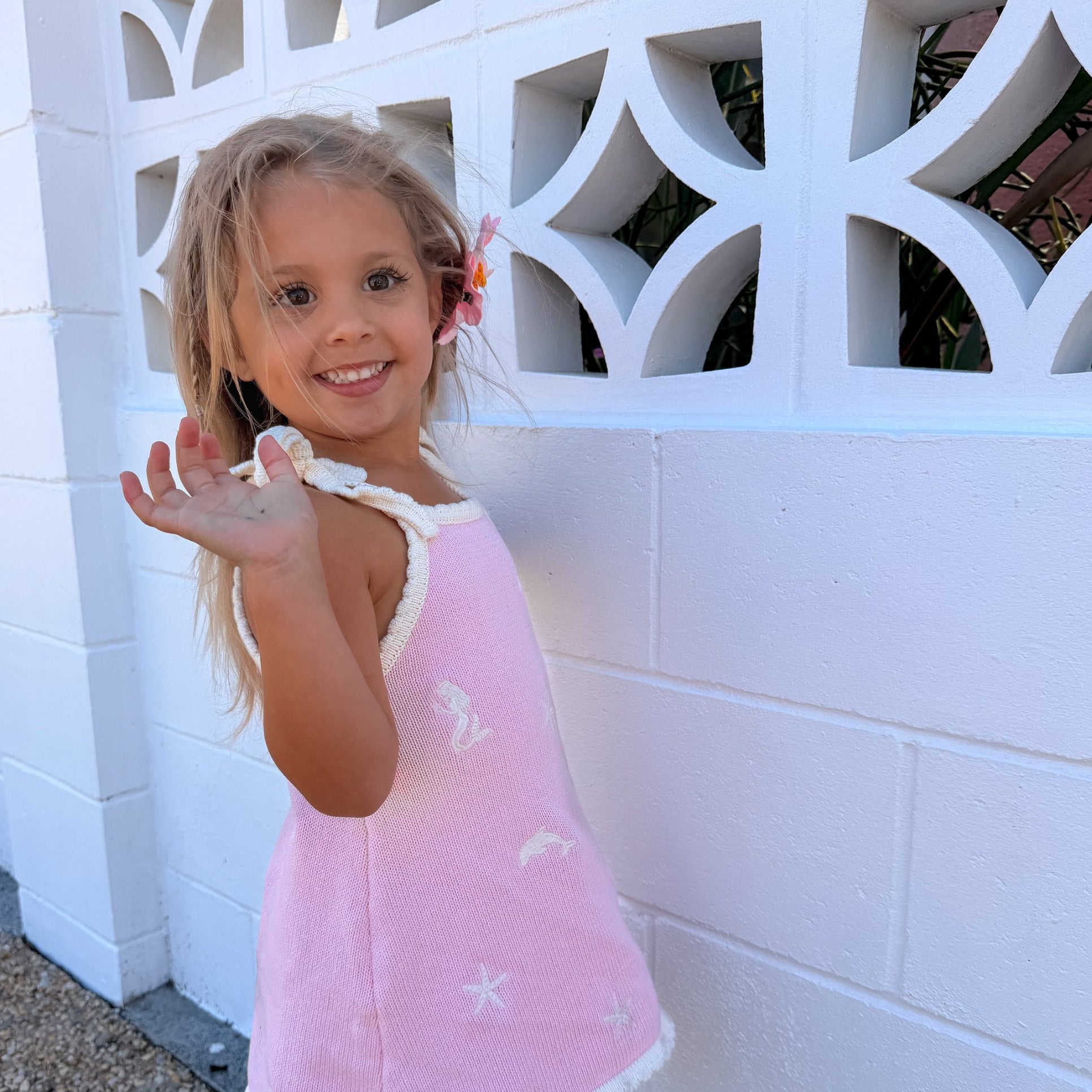 Pink dolphin knit sun dress, side view with tie straps and scalloped hem
