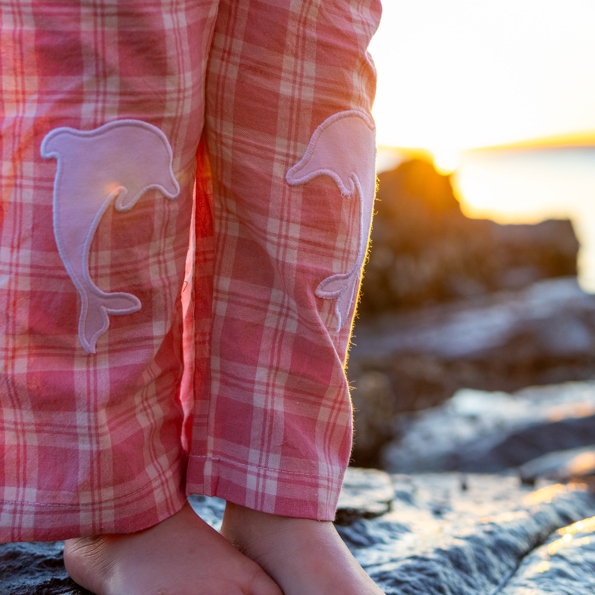 Little Dolphin Club Pants in pink check, close up of the white dolphin knee patches at golden hour
