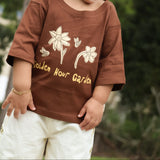 Child wearing the Golden Hour Garden Tee, close up of the hand drawn flower and bee print in buttery yellow