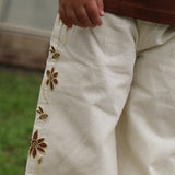 Close up of the embroidered flowers and bees down the leg of the Let's Pick Flowers Pants in cream linen