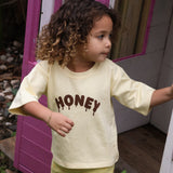 Child stepping out of a cubby house in the Sweet as Honey Tee and Buttercup Flares