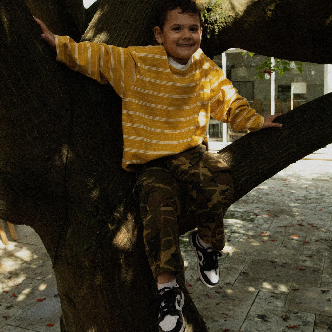 Boy in a tree wearing the Last Light Long Sleeve and Garden Explorer Cargos