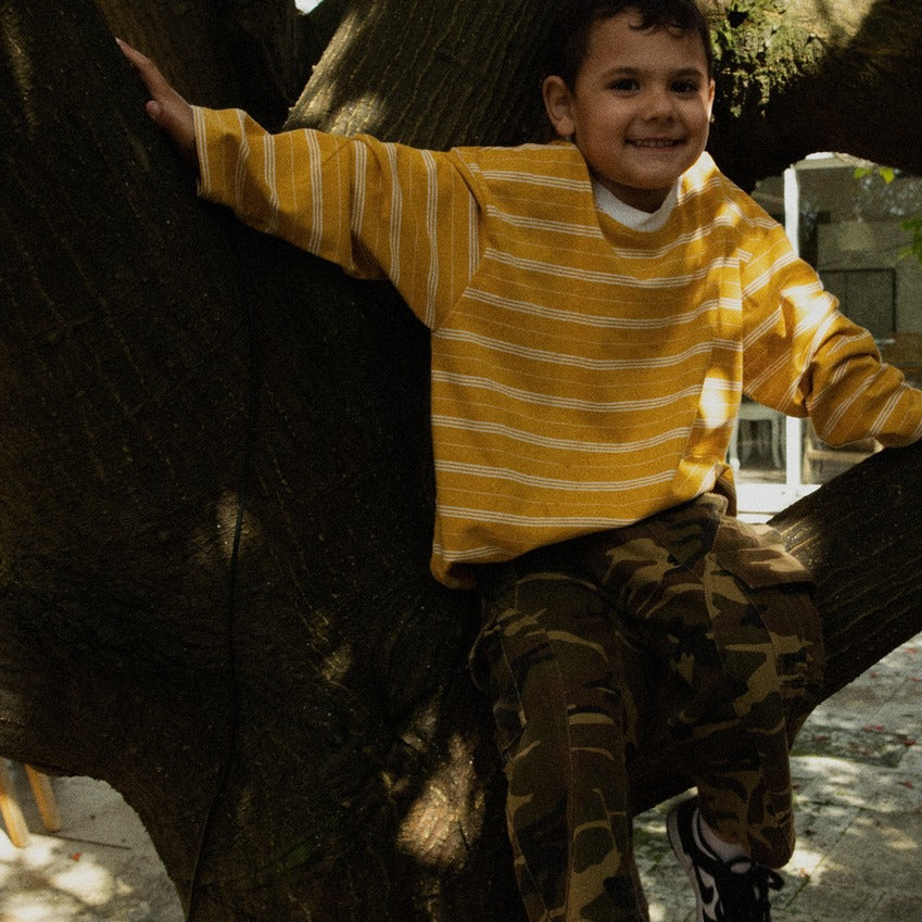 Boy in a tree wearing the Last Light Long Sleeve and Garden Explorer Cargos