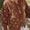 Child wearing the Honey Blossom Cardi in chocolate brown knit with cream polka dots, tie-up front and flower detail on the sleeve, paired with a white skirt